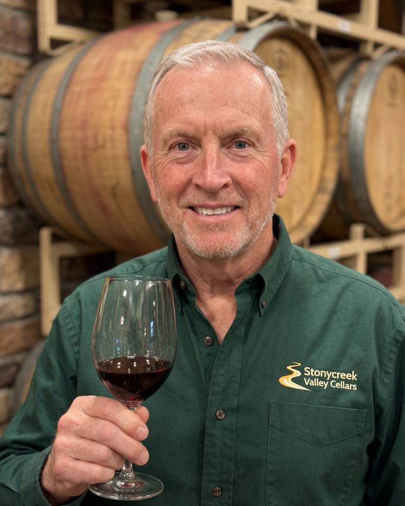 Winemaker Tom Hess holding a glass of red wine in the barrel room